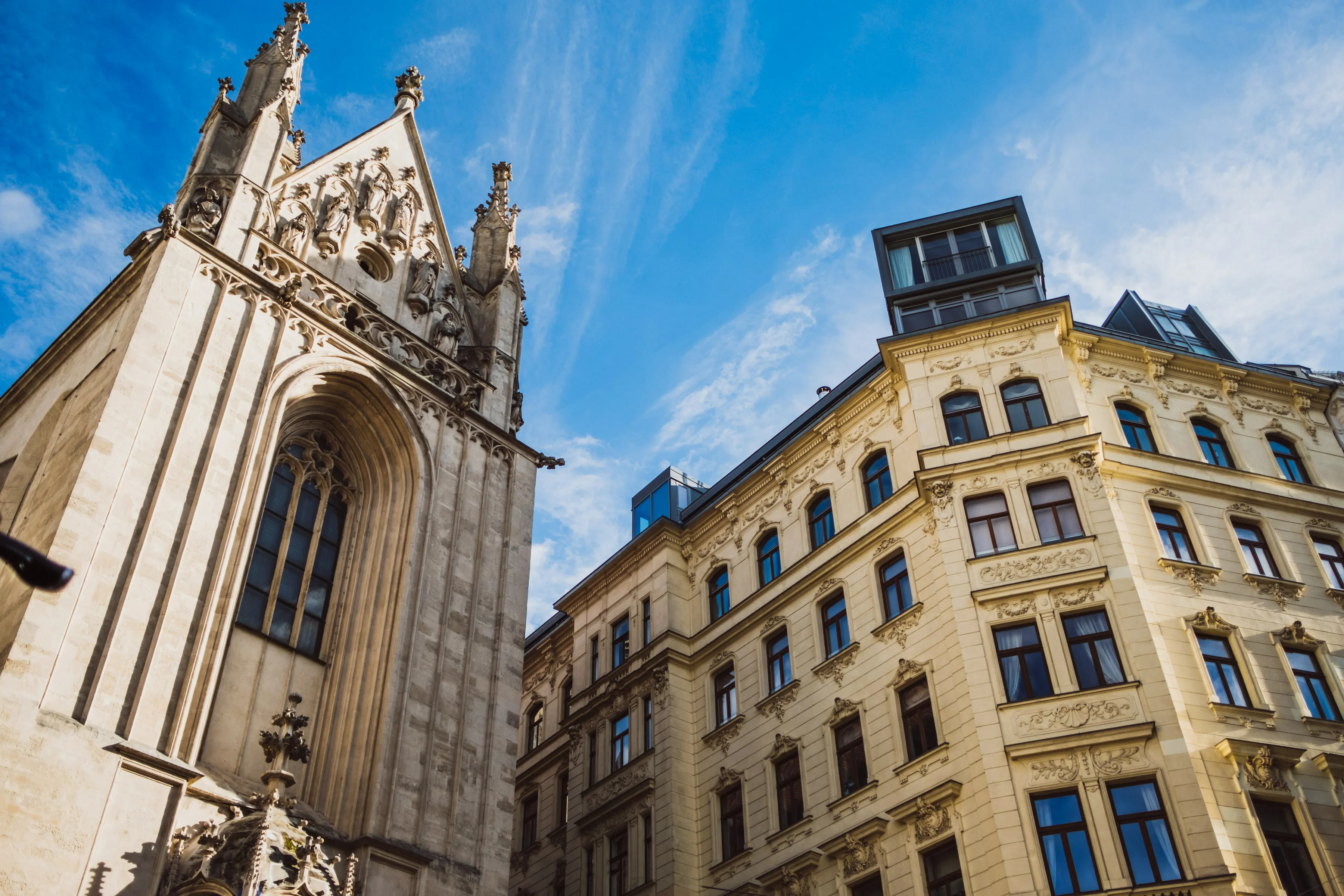 Blick hinauf zum Turm von Maria am Gestade und einer gelben Gründerzeitfassade