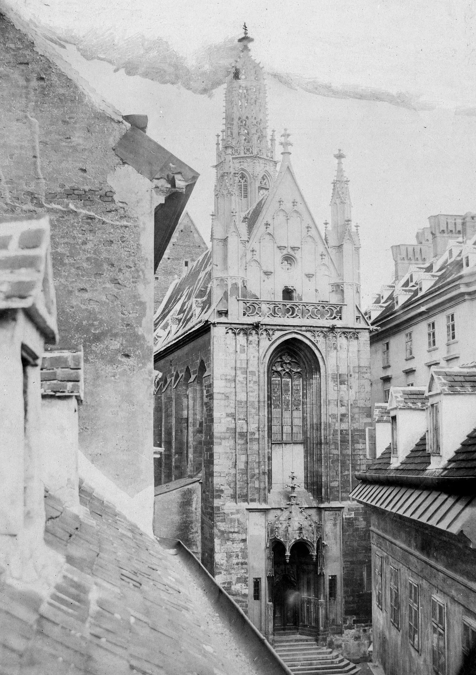 Historische Fotografie der Westfassade von Maria am Gestade mit gotischem Portal und Turm, umgeben von Dächern
