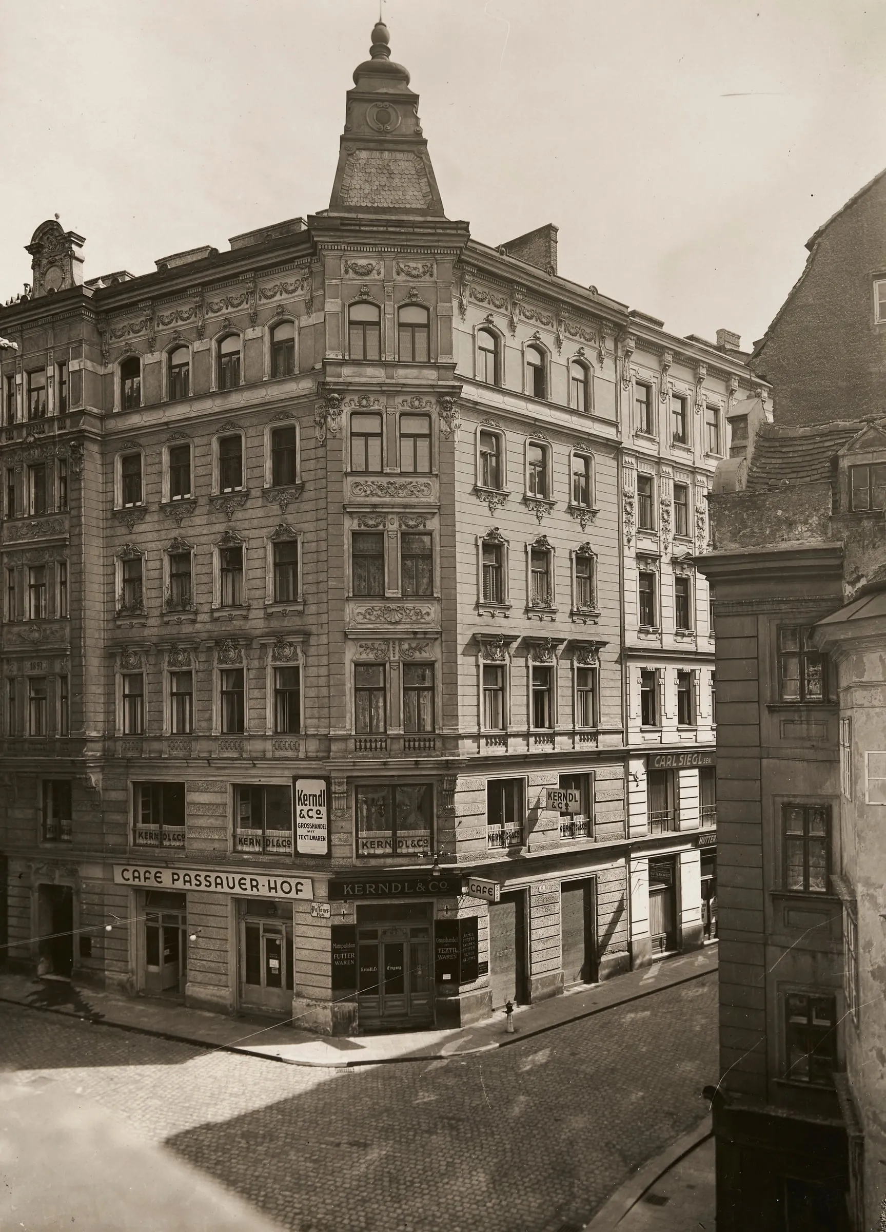 Schwarzweißfotografie des Eckhauses Passauer Platz 2 mit Turmaufsatz und dem Café Passauer Hof im Erdgeschoss